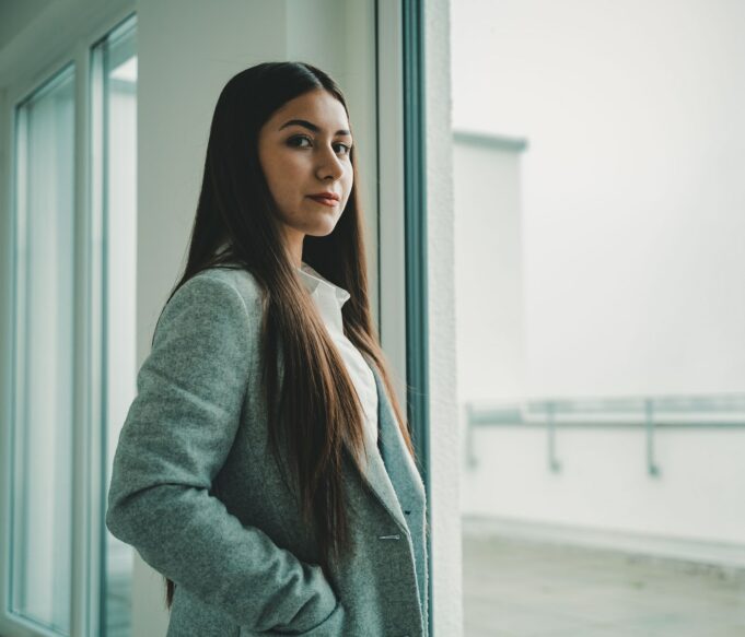 woman in gray sweater standing near window