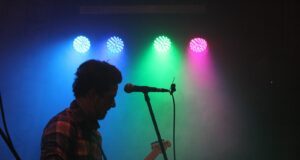 man playing guitar with stage lights