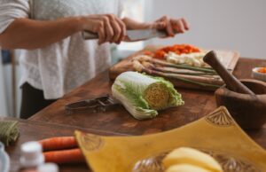 person slicing green vegetable on brown wooden chopping board