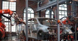 gray vehicle being fixed inside factory using robot machines