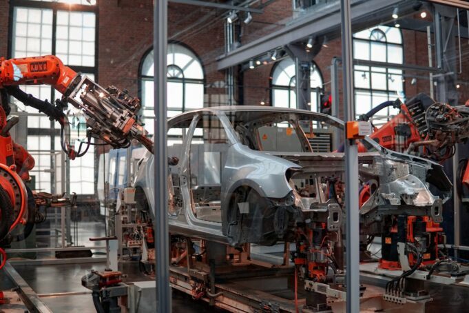 Industrie - Auto Foto von Lenny Kuhne gray vehicle being fixed inside factory using robot machines