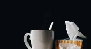white ceramic mug on white table beside black eyeglasses