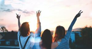 photo of three women lifting there hands 