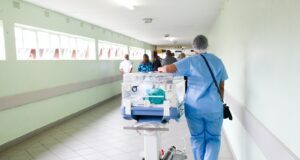 person walking on hallway in blue scrub suit near incubator
