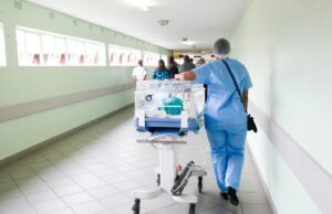 person walking on hallway in blue scrub suit near incubator