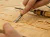 person using chisel while curving wood