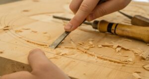 person using chisel while curving wood