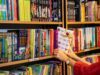 a woman is holding a gift in front of a book shelf