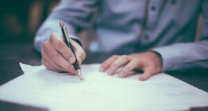 man writing on paper