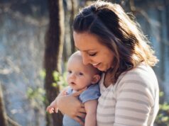 woman carrying baby near trees