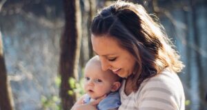 woman carrying baby near trees