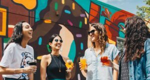 four women holding drinks while laughing together during daytime