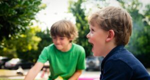 boy in blue shirt screaming near boy in green crew-neck shirt