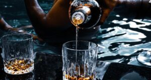 person pouring water on clear drinking glass