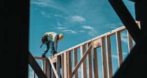 man in yellow shirt and blue denim jeans jumping on brown wooden railings under blue and