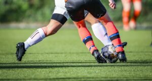 woman in black and white soccer jersey kicking soccer ball on green field during daytime