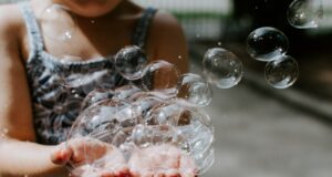 person holding soap bubbles outdoors