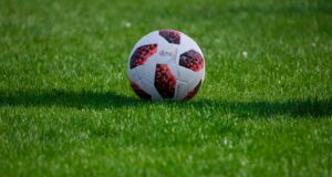 white and red soccer ball on green grass field during daytime