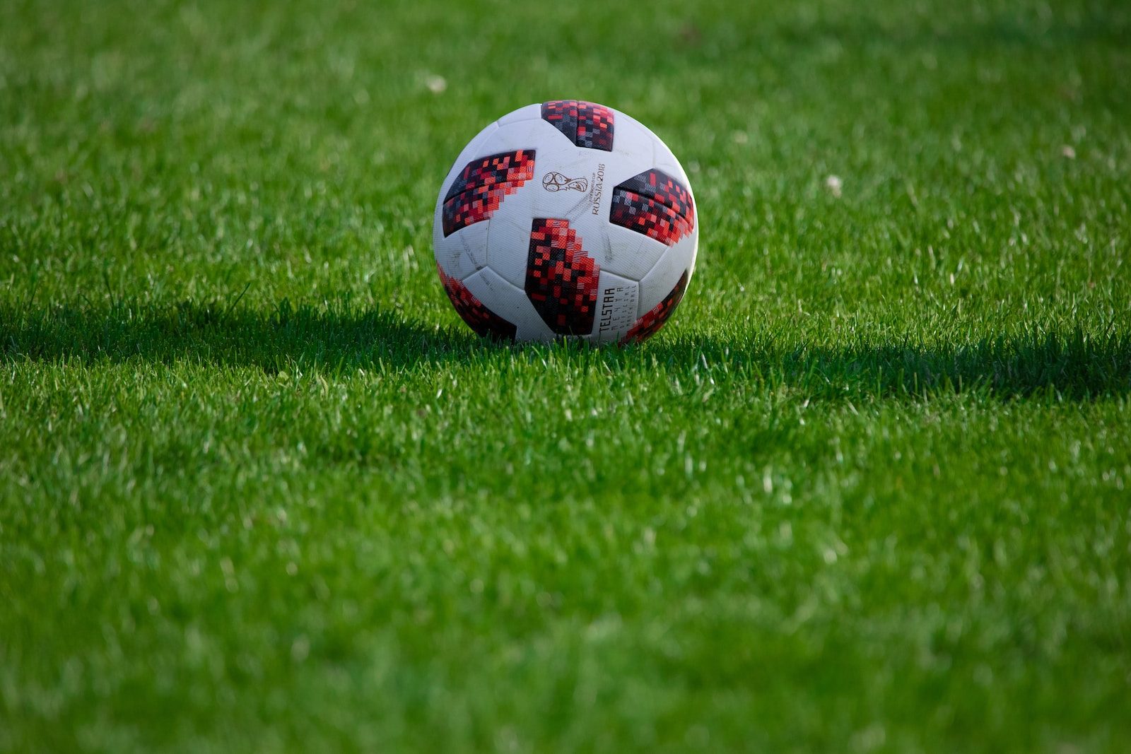 white and red soccer ball on green grass field during daytime