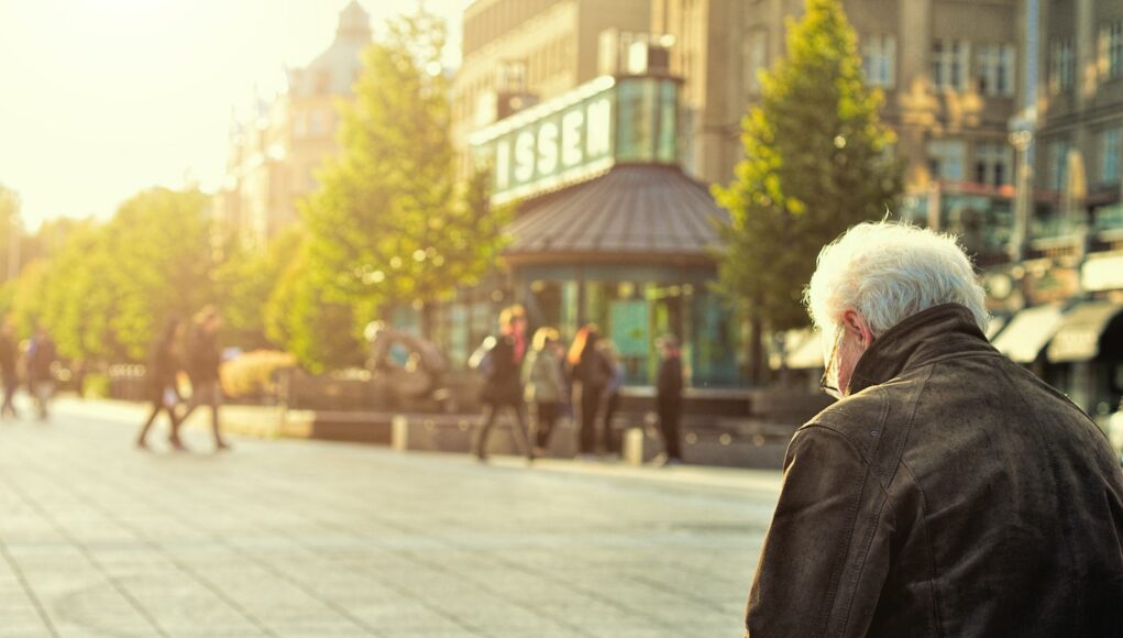 man sitting on brown wooden bench