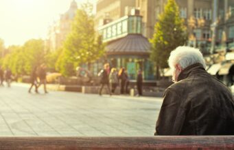 man sitting on brown wooden bench