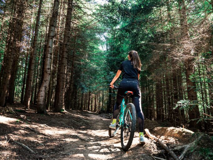 woman riding on blue bicycle inside forest