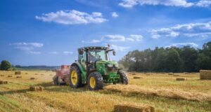 green tractor on brown grass field under blue sky during daytime