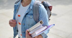 woman wearing blue denim jacket holding book