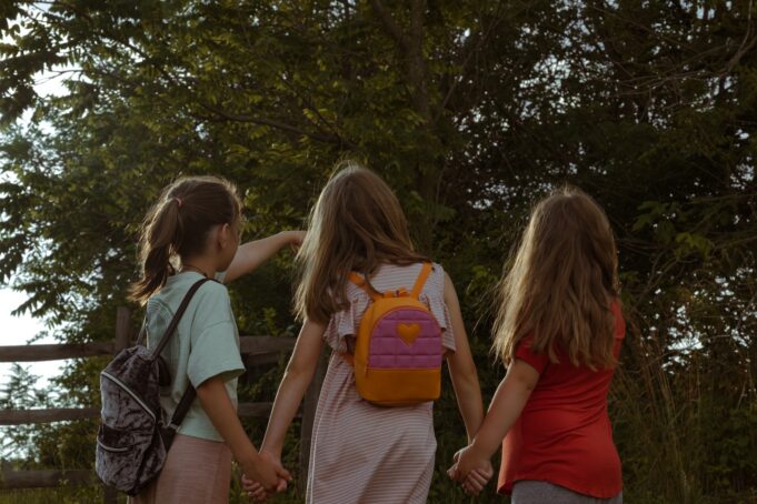 a group of young girls holding hands and walking