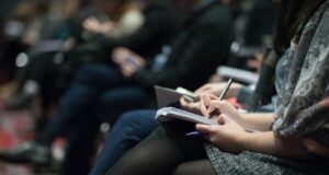 selective focus photography of people sitting on chairs while writing on notebooks