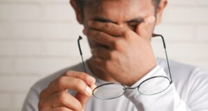 a man holding a pair of glasses up to his face