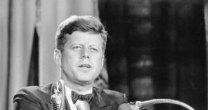 a man in a suit and tie standing at a podium