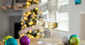 two clear footed wineglasses filled with yellow liquid near assorted-color ball ornaments
