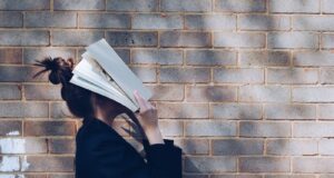 woman covering her face with white book