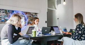 3 women sitting on chair in front of table with laptop computers