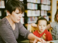 woman in gray long sleeve shirt sitting beside boy in orange crew neck shirt