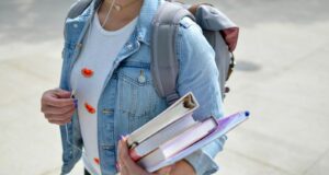 woman wearing blue denim jacket holding book