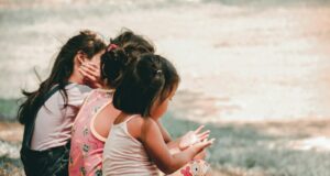 three children sitting on grass