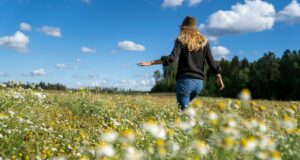 a woman walking through a field of wildflowers