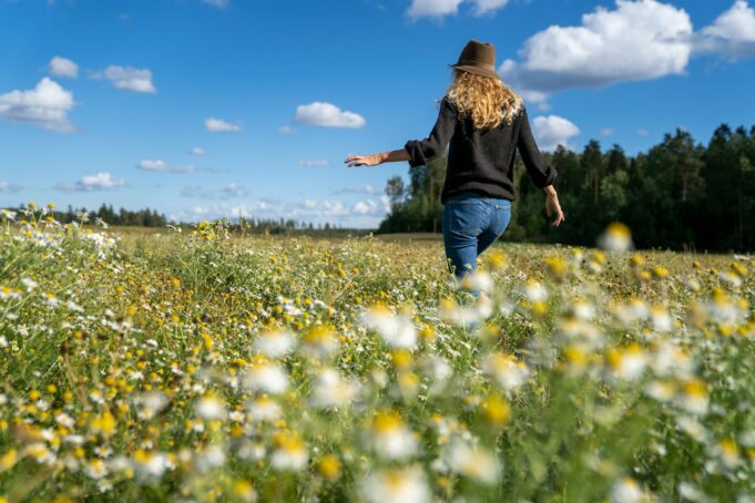 a woman walking through a field of wildflowers