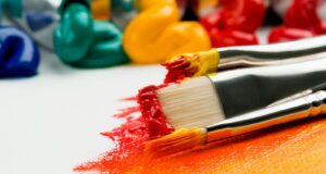 three silver paint brushes on white textile