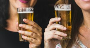 tow woman holding clear glass full drinking glasses