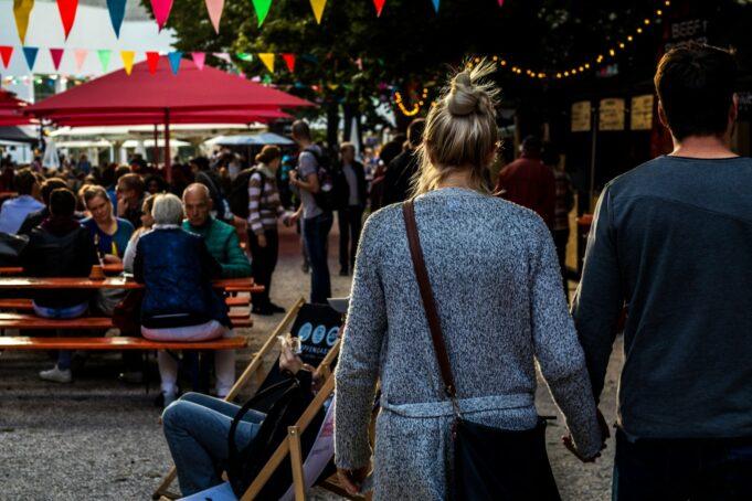 man and woman walking while holding hands during daytime