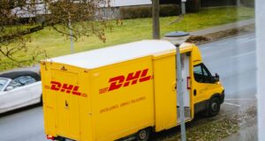 white and orange box truck parked near bare trees during daytime