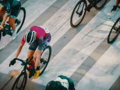 person in green and black shorts riding on black and red bicycle