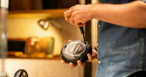 person in blue denim jeans holding black and gray corded headphones