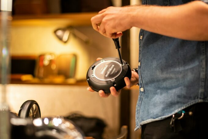 person in blue denim jeans holding black and gray corded headphones