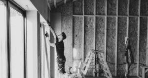 a black and white photo of a man working on a wall