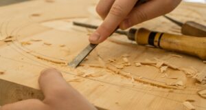 person using chisel while curving wood