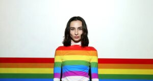 a woman standing in front of a rainbow colored wall
